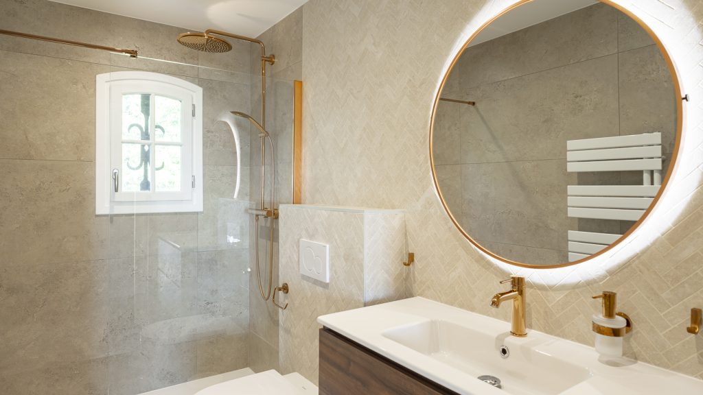 Bathroom with a walk-in shower and round mirror at Tanneron Villa