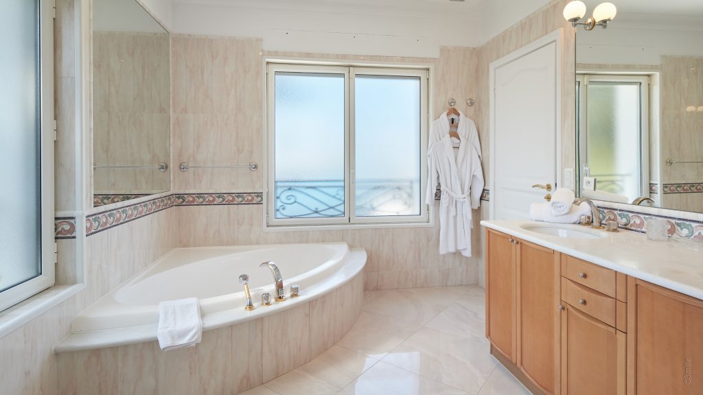 Bathroom with a corner bath and sea-view window at Villa Mareclaire