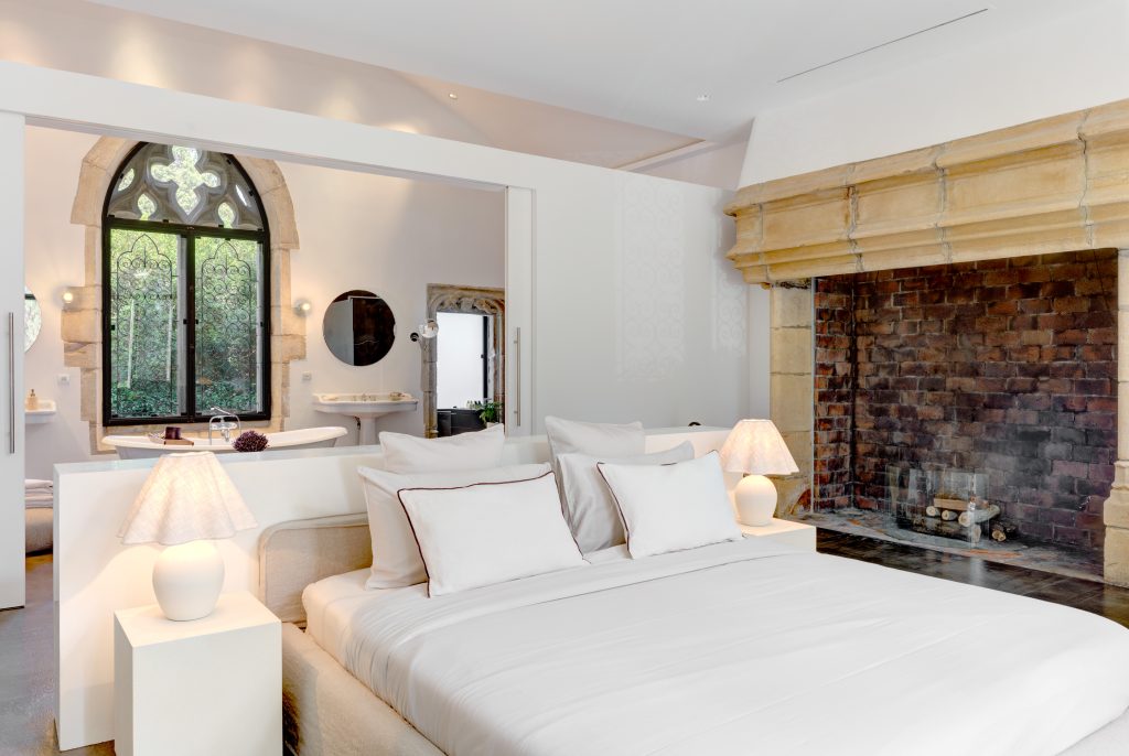 Le Castel master bedroom with fireplace and stone window
