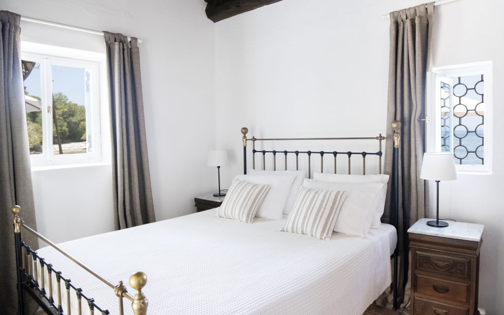 Bedroom with an iron bed and white linen at Kastalia Estate