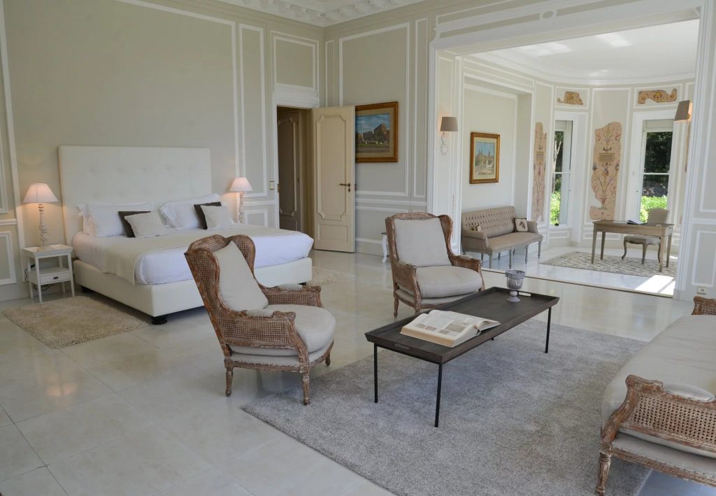 Bedroom with a white double bed and sitting area at Domaine de l’Epoque