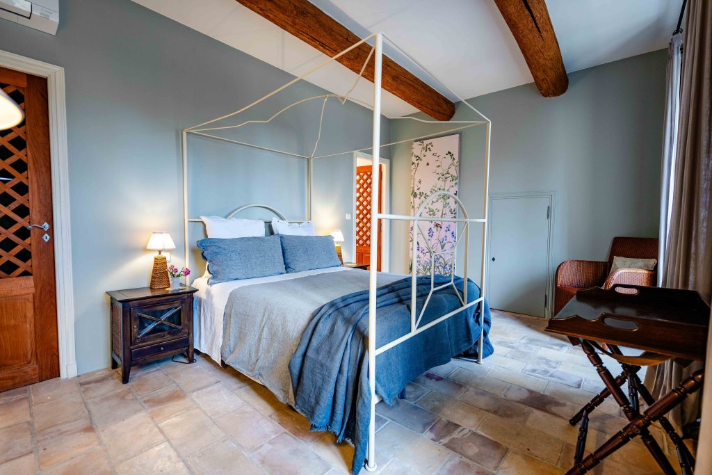 Bedroom with a canopy bed and exposed beams at Domaine du Levant