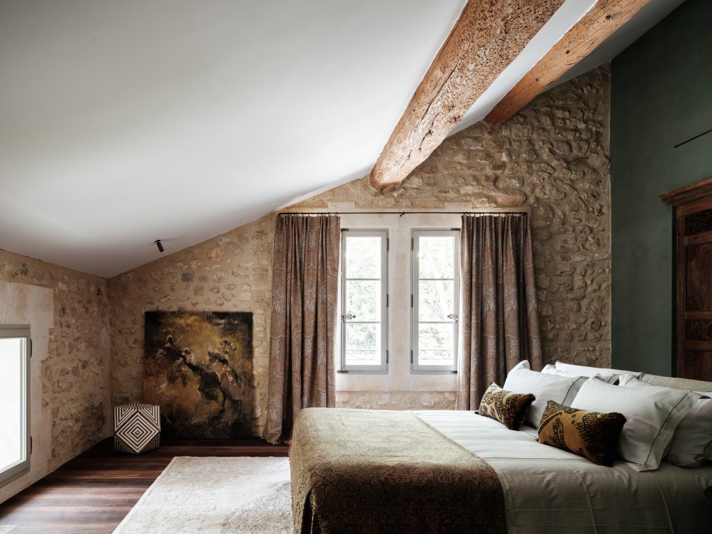 Bedroom with stone walls and beamed ceiling at Mas des Oliviers