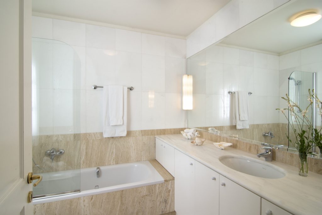 Bathroom with a bathtub and glass shower at Villa Eos