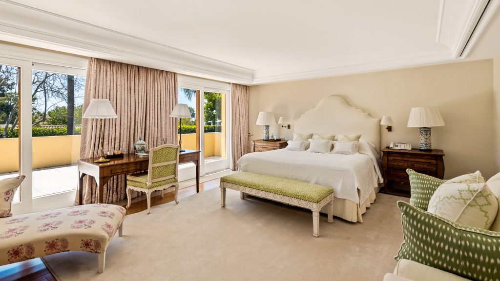 Bedroom with a cream upholstered headboard and a bench at the foot of the bed at Monte Mar Estate