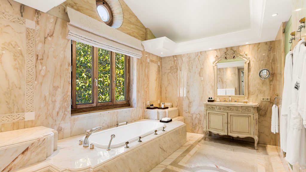 Marble bathroom with a bathtub beneath a window at Monte Mar Estate