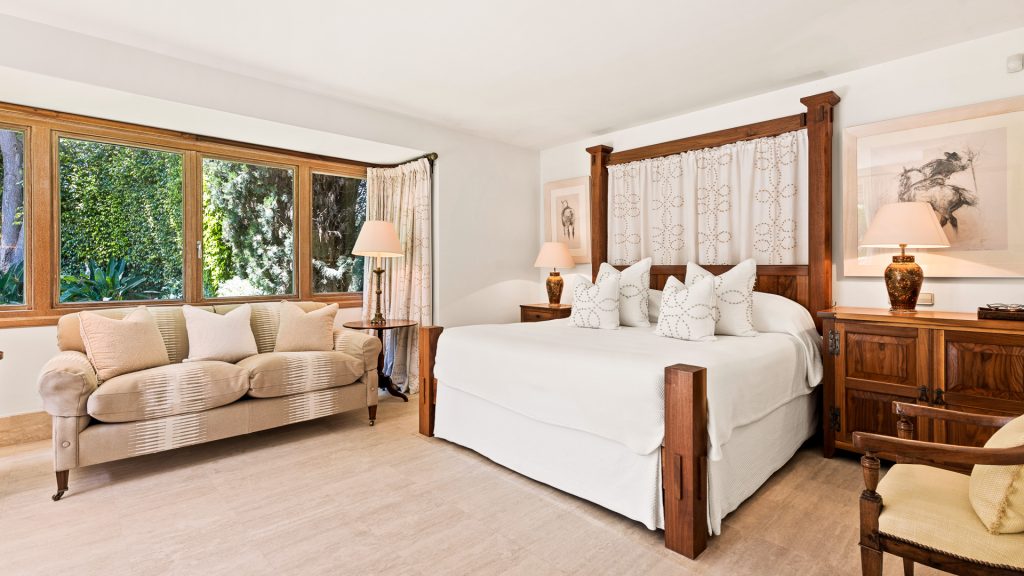 Bedroom with a wooden headboard and a sofa by the window at Monte Mar Estate