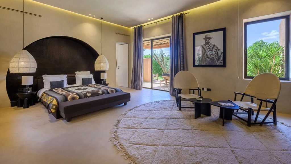 Suite with a dark arched headboard and garden doors at Villa Palmeraie
