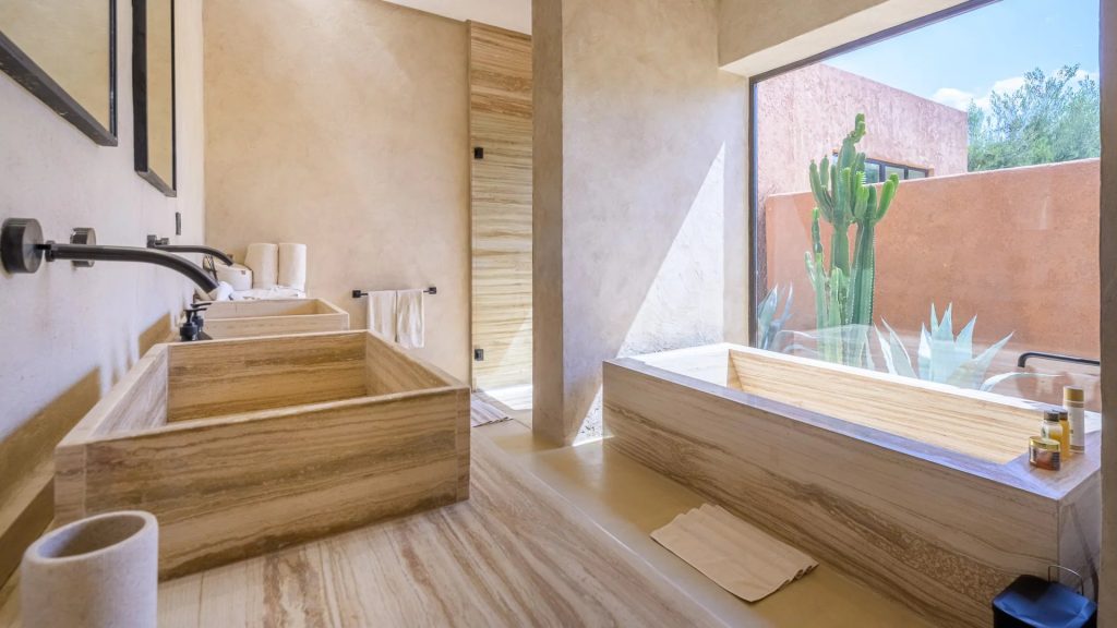 Bathroom with a stone bathtub and garden view at Villa Palmeraie